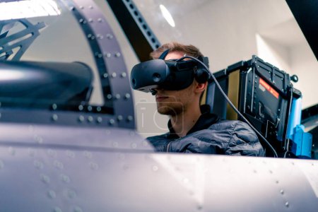 Photo for Boy sitting in flight simulator military plane wearing virtual reality glasses during flight entertainment - Royalty Free Image
