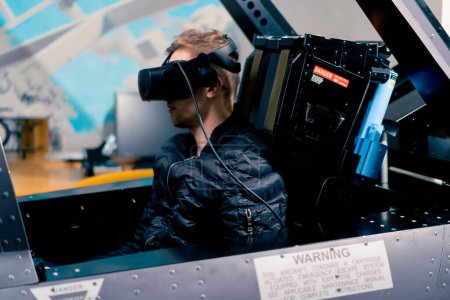 Foto de Niño sentado en avión militar simulador de vuelo con gafas de realidad virtual durante el entretenimiento de vuelo - Imagen libre de derechos