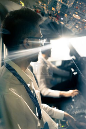 Photo for Young pilots in the cockpit of the plane control the air transport during the flight the sun shines from window in the far distance simulator - Royalty Free Image