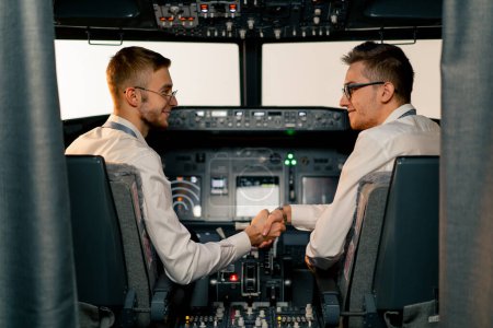 Foto de Pilotos en la cabina del avión se saludan y se dan la mano antes del inicio del vuelo - Imagen libre de derechos