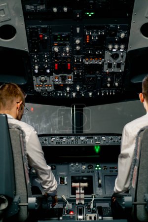 Photo for Rear view of pilots in the cockpit of an airplane during flight control in turbulence zone flight simulator - Royalty Free Image