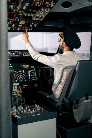 Foto de Cabina del avión El piloto comprueba la electrónica del avión pulsando los botones Preparando el revestimiento de pasajeros para el despegue - Imagen libre de derechos