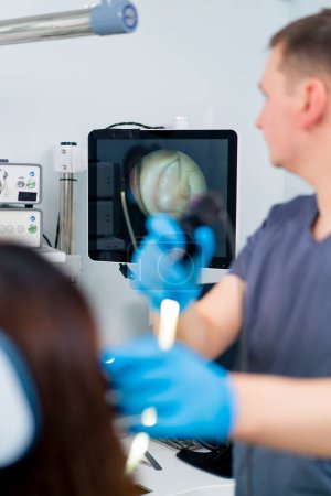 Photo for An ENT doctor performs an endoscopy procedure on a patient's ear in clinic holding a professional device in his hand - Royalty Free Image