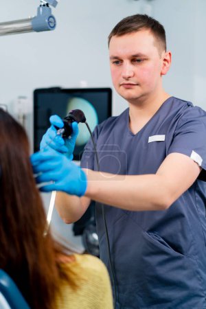 Foto de Un médico otorrinolaringólogo realiza un procedimiento endoscópico en el oído de un paciente en una clínica con un dispositivo profesional en la mano - Imagen libre de derechos