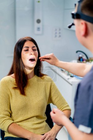 Photo for The ENT doctor examines the patient in the office of the clinic, checks the oral and nasal cavity ear canals with professional instruments - Royalty Free Image