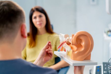 an ENT doctor consults a patient in the clinic's office tells about the possible consequences of the operation shows ear and nasal canals