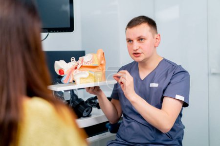 Photo for An ENT doctor consults a patient in the clinic's office tells about the possible consequences of the operation shows ear and nasal canals - Royalty Free Image