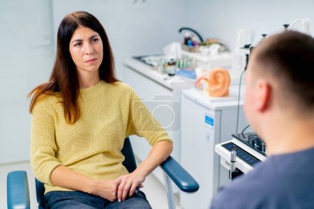 Photo for The ENT doctor consults the patient in the office of the clinic and tells about the possible consequences of operation - Royalty Free Image