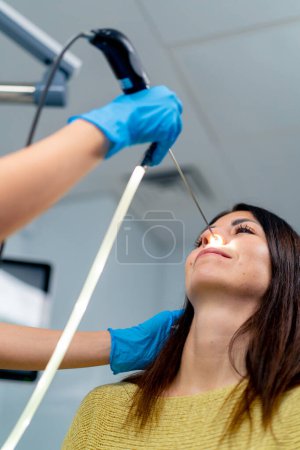 Foto de Primer plano el médico otorrinolaringólogo realiza el procedimiento de endoscopia de la nariz del paciente en la clínica con dispositivo profesional en la mano - Imagen libre de derechos