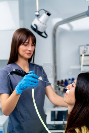 Foto de El médico otorrinolaringólogo realiza el procedimiento de endoscopia de la nariz del paciente en la clínica con dispositivo profesional en la mano - Imagen libre de derechos