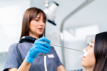 Photo for The ENT doctor performs the procedure of endoscopy of the patient's nose in the clinic holding professional device in his hand - Royalty Free Image