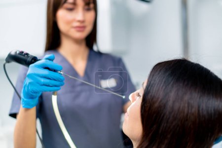 Photo for Close-up the ENT doctor performs the procedure of endoscopy of the patient's nose in the clinic holding professional device in his hand - Royalty Free Image