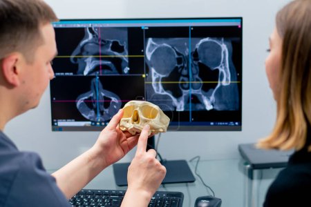 Photo for The radiologist doctor looks at the screen on which the 3D image of the nose scan shows the patient what needs be changed during surgery - Royalty Free Image