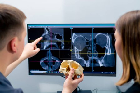 Téléchargez les photos : Le médecin radiologue regarde l'écran sur lequel l'image 3D de la numérisation du nez montre au patient ce qui doit être changé pendant la chirurgie - en image libre de droit