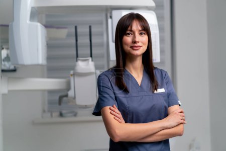 Photo for Portrait of a beautiful young female doctor dentist or radiologist in uniform standing with crossed arms in beauty and health clinic - Royalty Free Image