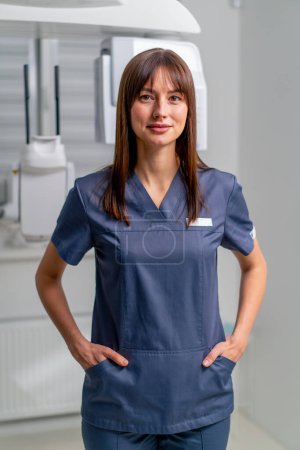 Téléchargez les photos : Portrait d'une belle jeune femme médecin dentiste ou radiologue en uniforme debout avec les bras croisés dans une clinique de beauté et de santé - en image libre de droit