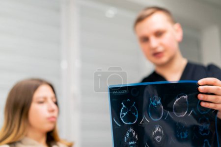 Téléchargez les photos : Le médecin montre une image d'une tomographie cérébrale à un patient malade à l'hôpital et parle du plan de traitement - en image libre de droit