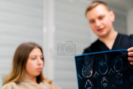 Photo for The doctor shows a picture of a brain tomography to a sick patient in the hospital and tells about treatment plan - Royalty Free Image