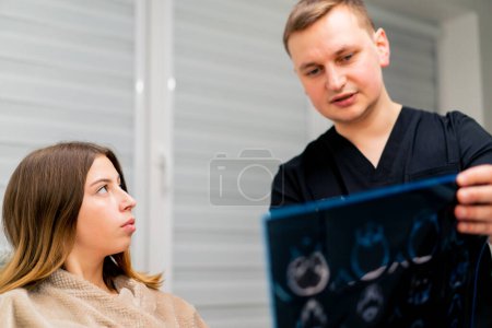 Foto de El médico le muestra una imagen de una tomografía cerebral a un paciente enfermo en el hospital y le informa sobre el plan de tratamiento - Imagen libre de derechos