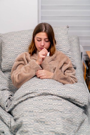 Foto de Un paciente enfermo en un hospital está acostado en una cama estornudando y sufriendo de secreción nasal tos y dolores de cabeza - Imagen libre de derechos