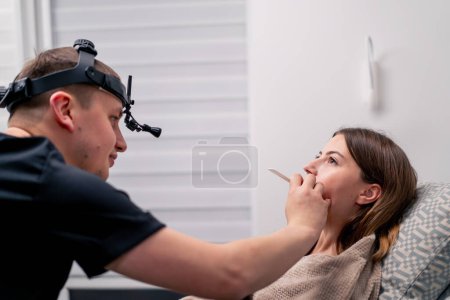 Foto de El médico otorrinolaringólogo examina la cavidad oral del paciente en el consultorio del policlínico con herramientas profesionales - Imagen libre de derechos