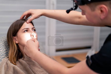 Téléchargez les photos : ORL médecin examine la cavité nasale du patient dans le bureau de la clinique avec des outils professionnels - en image libre de droit