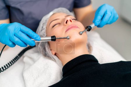 Téléchargez les photos : Gros plan d'un esthéticien massant la peau du visage d'un client pendant la procédure cosmétique de beauté et de santé - en image libre de droit