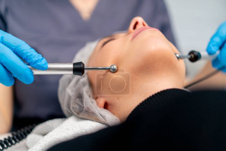 Foto de Primer plano de un médico esteticista masajeando la piel de la cara de un cliente durante el procedimiento cosmético de belleza y salud - Imagen libre de derechos