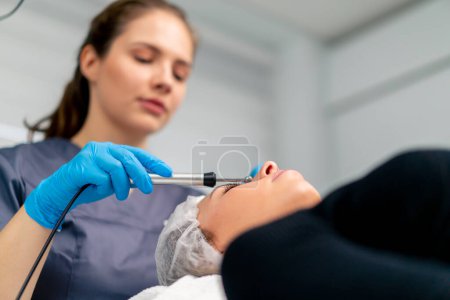 Photo for A beautician doctor massaging the skin of a client's face during beauty and health cosmetic procedure - Royalty Free Image