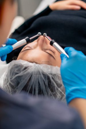 Photo for Close-up of a beautician doctor massaging the skin of a client's face during beauty and health cosmetic procedure - Royalty Free Image