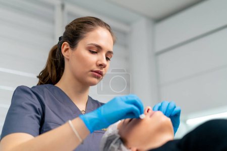 Foto de Retrato de un médico esteticista limpiando la piel de un cliente con una esponja de algodón antes de comenzar el procedimiento de belleza y salud - Imagen libre de derechos