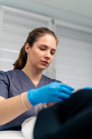 Foto de Retrato de un médico esteticista limpiando la piel de un cliente con una esponja de algodón antes de comenzar el procedimiento de belleza y salud - Imagen libre de derechos