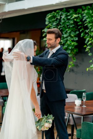 Foto de Retrato de amantes felices el novio levanta el velo de la novia en un vestido blanco en el altar los recién casados en la boda - Imagen libre de derechos