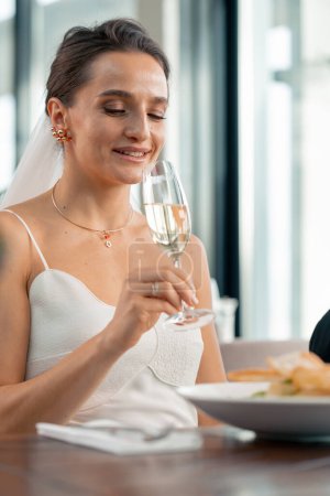 Foto de Retrato de una hermosa novia sonriente en una boda en un restaurante durante la celebración del amor con una copa de champán - Imagen libre de derechos
