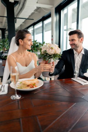 Téléchargez les photos : Portrait d'amoureux souriants marié donnant bouquet à la mariée jeunes mariés au mariage au restaurant pendant la célébration romance d'amour - en image libre de droit