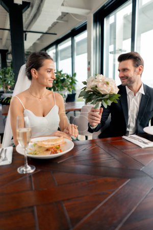 Photo for Portrait of smiling lovers groom giving bouquet to bride newlyweds at wedding in restaurant during celebration love romance - Royalty Free Image