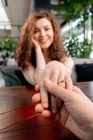 Téléchargez les photos : Gros plan d'une date dans un restaurant une femme s'assoit avec une alliance à son doigt après une demande en mariage romantique - en image libre de droit