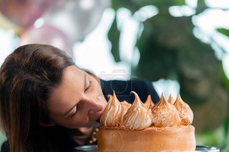 Photo for Portrait of happy birthday girl biting celebration cake during party restaurant with gifts - Royalty Free Image