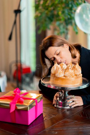 Photo for Portrait of happy birthday girl biting celebration cake during party restaurant with gifts - Royalty Free Image