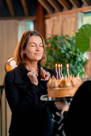 Foto de Retrato de la chica feliz cumpleaños mirando pastel de cumpleaños y pidiendo deseo soplando velas durante la fiesta en el restaurante - Imagen libre de derechos