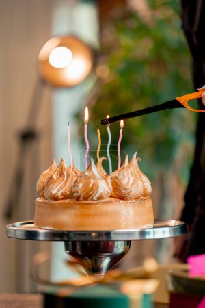 Foto de Primer plano de un delicioso pastel apetitoso durante una celebración de cumpleaños en un restaurante persona enciende una vela - Imagen libre de derechos
