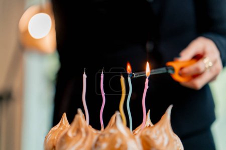 Foto de Primer plano de un delicioso pastel apetitoso durante una celebración de cumpleaños en un restaurante persona enciende una vela - Imagen libre de derechos