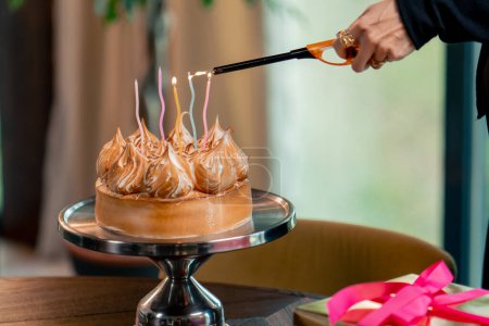 Téléchargez les photos : Gros plan d'un délicieux gâteau appétissant lors d'une célébration d'anniversaire dans un restaurant personne allume une bougie - en image libre de droit