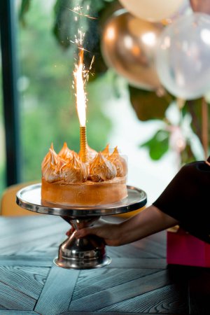 Téléchargez les photos : Gros plan de délicieux gâteau appétissant avec bougie allumée pendant la célébration d'anniversaire restaurant - en image libre de droit