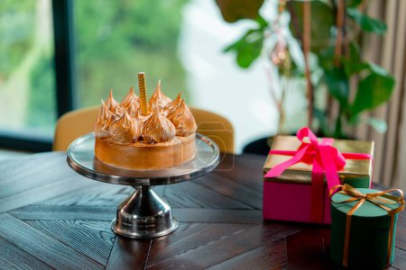 Foto de Primer plano de un delicioso pastel apetitoso con una vela de pie en un stand durante una fiesta de cumpleaños en el restaurante - Imagen libre de derechos
