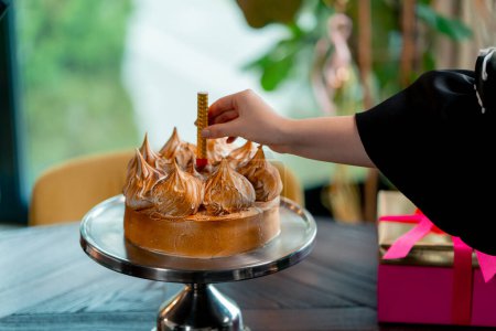 Téléchargez les photos : Gros plan de délicieux appétissant gâteau main met bougie lors de la célébration d'anniversaire restaurant - en image libre de droit