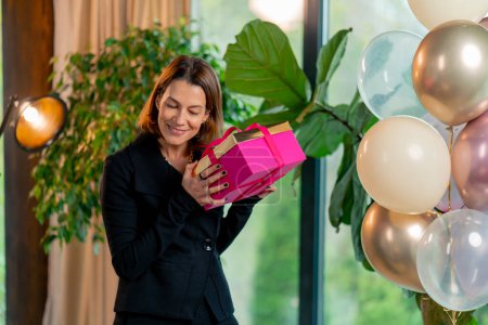 Foto de Retrato de una niña feliz cumpleaños femenino sosteniendo una caja de regalo brillante durante una celebración de cumpleaños en el restaurante - Imagen libre de derechos