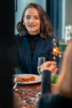 Foto de Retrato de una hermosa mujer sonriente sosteniendo un bengala durante una celebración de cumpleaños en un restaurante en la compañía de amigos - Imagen libre de derechos