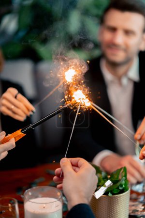 Téléchargez les photos : Gros plan d'un groupe d'amis allumant des étincelles lors d'une célébration d'anniversaire au restaurant - en image libre de droit