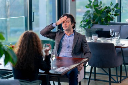 Photo for Portrait of an upset nervous man sitting in a restaurant with a girl who is quarreling on date conflict - Royalty Free Image
